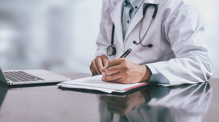Medico che compila la certificazione per la riapertura infortunio INAIL e la riammissione in temporanea