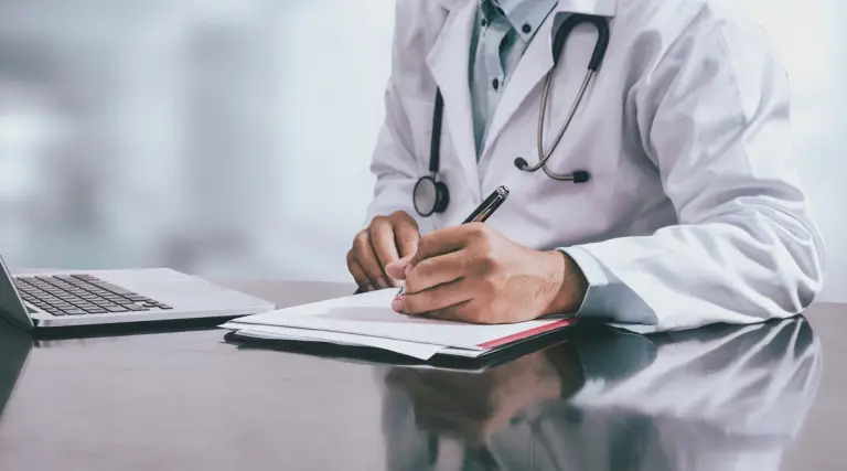Medico che compila la certificazione per la riapertura infortunio INAIL e la riammissione in temporanea