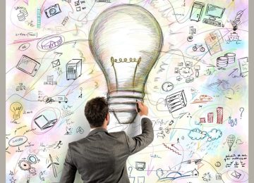 Un professionista di spalle disegna una grande lampadina circondata da icone di tecnologia energetica e sostenibilità.