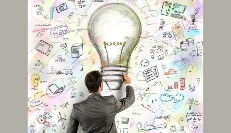 Un professionista di spalle disegna una grande lampadina circondata da icone di tecnologia energetica e sostenibilità.