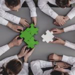 Un team di professionisti lavora insieme per completare un puzzle, simbolo della rendicontazione di sostenibilità e della collaborazione strategica nel reporting aziendale