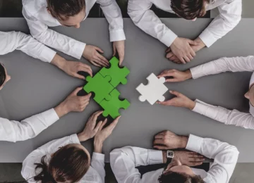 Un team di professionisti lavora insieme per completare un puzzle, simbolo della rendicontazione di sostenibilità e della collaborazione strategica nel reporting aziendale