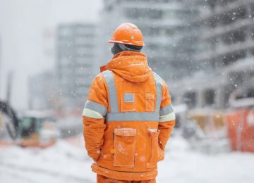 Lavoratore in cantiere durante l’inverno esposto a stress termico da freddo.