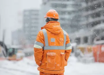 Lavoratore in cantiere durante l’inverno esposto a stress termico da freddo.