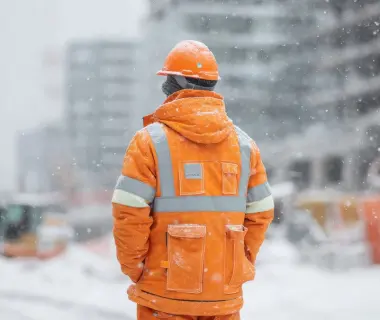 Lavoratore in cantiere durante l’inverno esposto a stress termico da freddo.