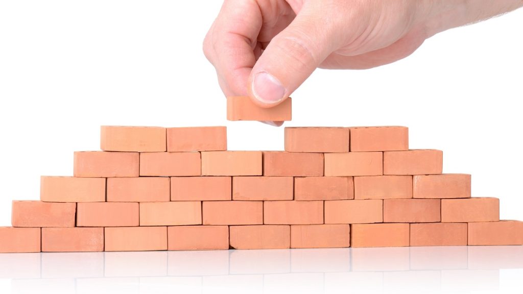 Mano che conclude muro di mattoni. Simbolo Codice Edilizia e stato legittimo immobili.