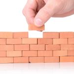 Mano che conclude muro di mattoni. Simbolo Codice Edilizia e stato legittimo immobili.