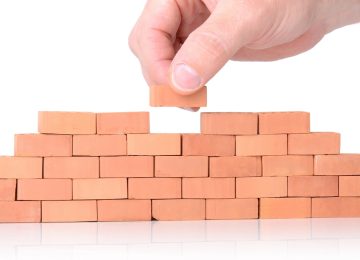 Mano che conclude muro di mattoni. Simbolo Codice Edilizia e stato legittimo immobili.