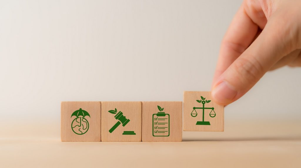 Illustrazione concettuale su cubi di legno delle novità ambientali nella Legge di Bilancio 2026: normativa, controlli e tutela del territorio.