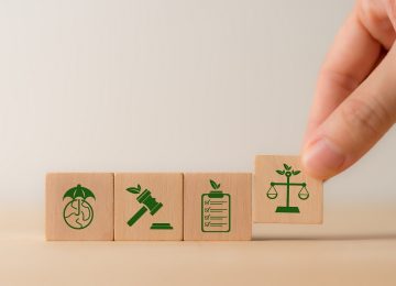 Illustrazione concettuale su cubi di legno delle novità ambientali nella Legge di Bilancio 2026: normativa, controlli e tutela del territorio.