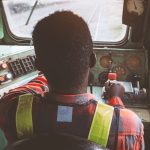 Veduta interna della cabina di guida di un treno con macchinista al lavoro: focus sulla vigilanza e sicurezza ferroviaria.