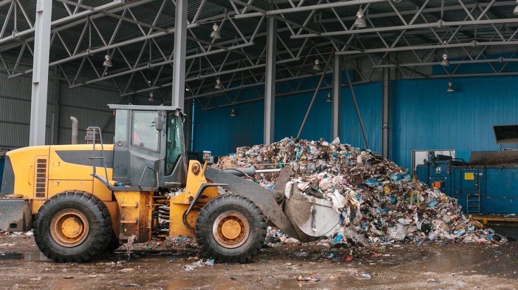 Gestione e rimozione di depositi di rifiuti storici con mezzi meccanici in area industriale.
