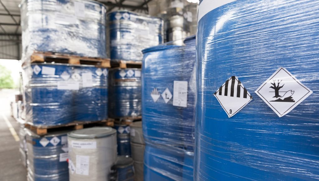 Imballaggi industriali contaminati da sostanze pericolose in area di stoccaggio