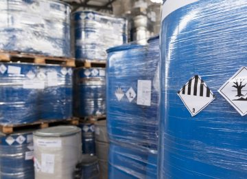 Imballaggi industriali contaminati da sostanze pericolose in area di stoccaggio