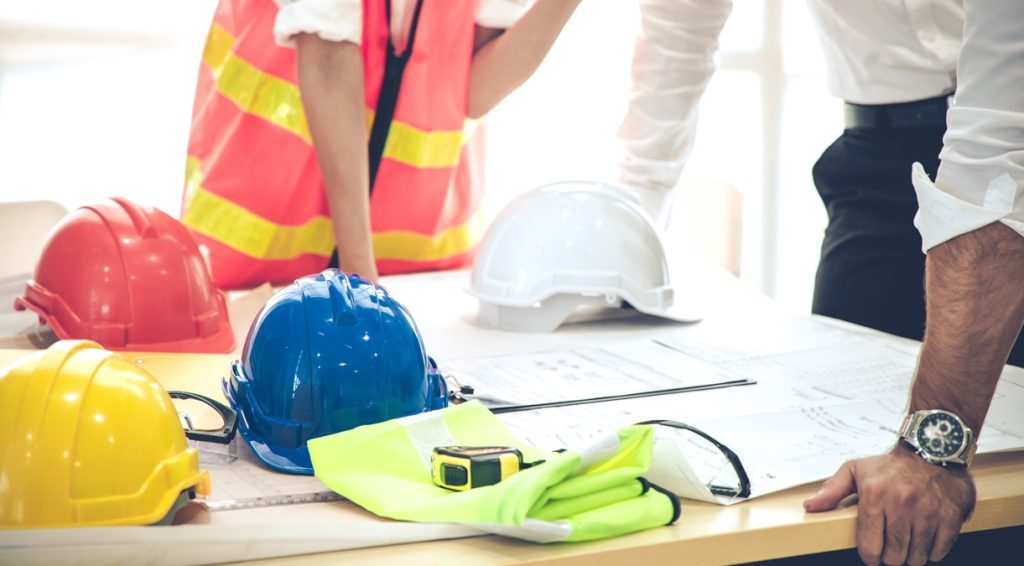 Riunione di coordinamento su progetti di cantiere con caschi protettivi: focus su governance dei rischi e prevenzione near miss.