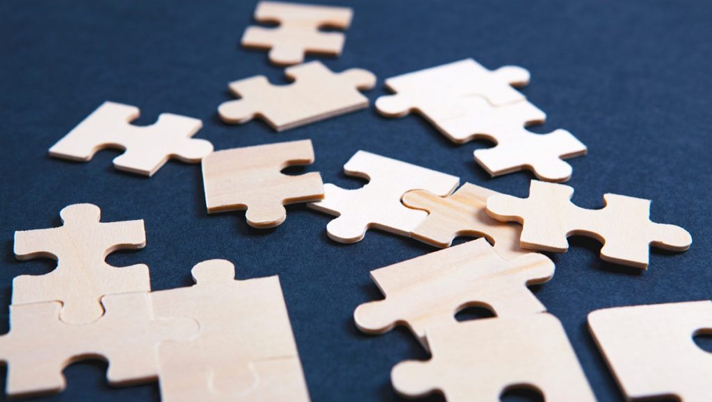 Pezzi di puzzle in legno sparsi su sfondo scuro, metafora delle criticità interpretative del nuovo Accordo Stato-Regioni sulla formazione sicurezza.